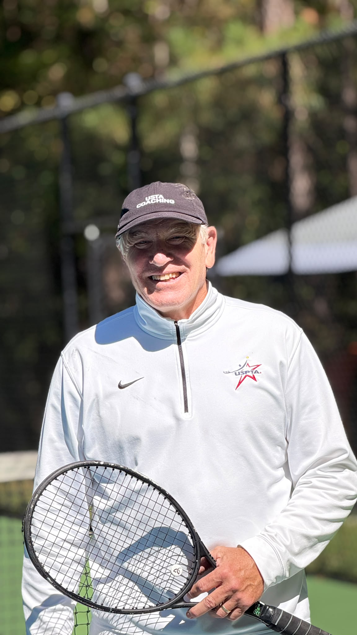Tennis coach Robert Allen Gibson holding a racket on court
