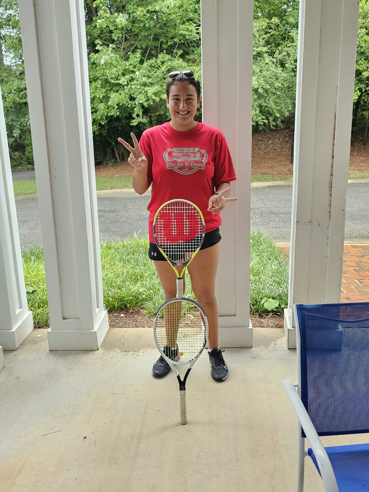 Teen tennis student smiling with two rackets