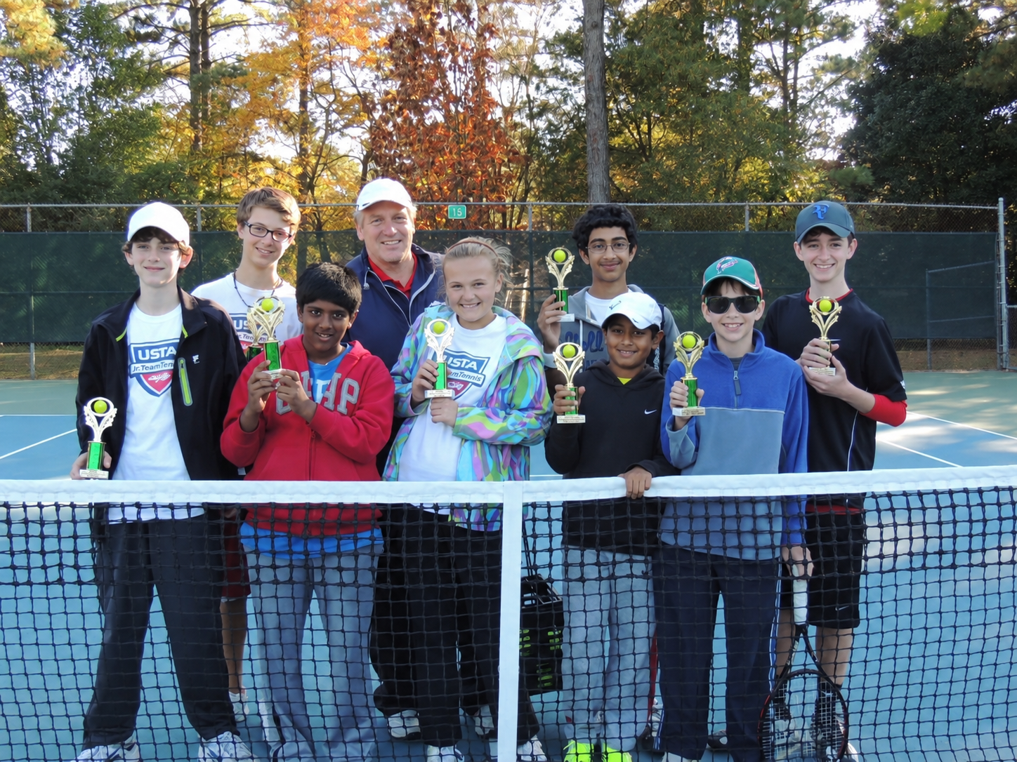 Coach Robert with junior tennis players holding their trophies